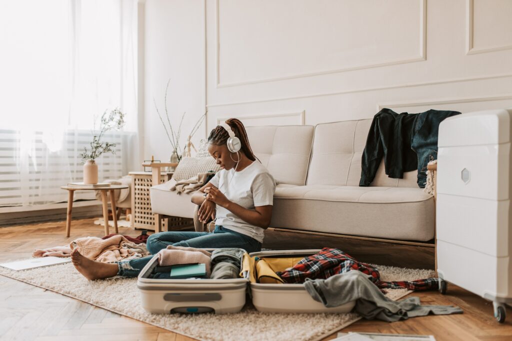 Woman sitting in living room packing luggage